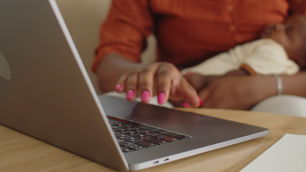 Woman Talking with Colleagues on Video on Laptop Holding Newborn Daughter