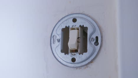 person turning off the light switch before leaving the house