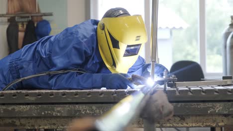 man wearing mask welding in a workshop. metal workers use manual labor. skilled welder. welder is welding the stainless steel pipes in the factory. welder industrial part in factory.