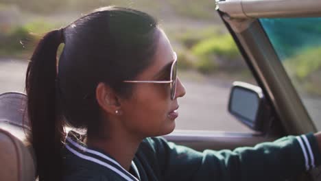 african american woman driving along country road in convertible car