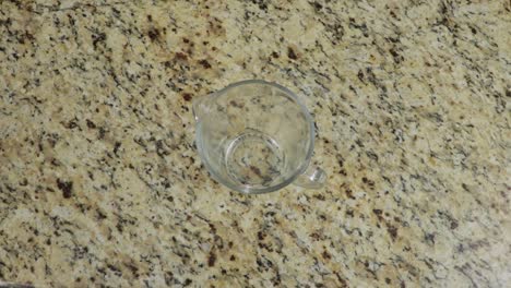 Putting-empty-glass-measuring-cup-on-a-table,-top-down-view