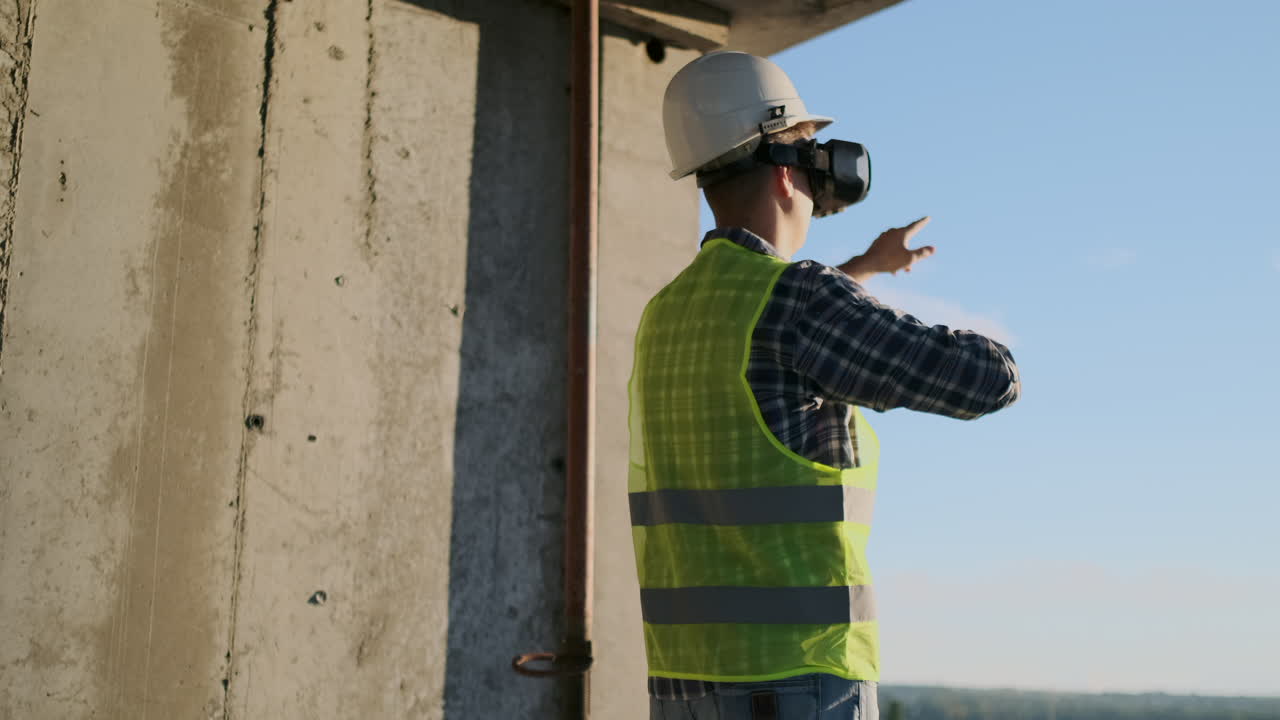 el ingeniero constructor visualiza el plan del edificio de pie en el techo del edificio al atardecer se encuentra en gafas vr y mueve sus manos usando la interfaz del futuro.