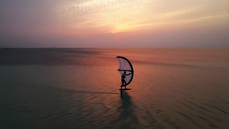 wing foiling on calm water at sunset