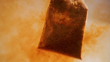 close up of tea bag diffusing in a clear glass. macro slow motion shot of the process of brewing herbal.