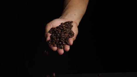man hand holding roasted coffee beans, slow motion