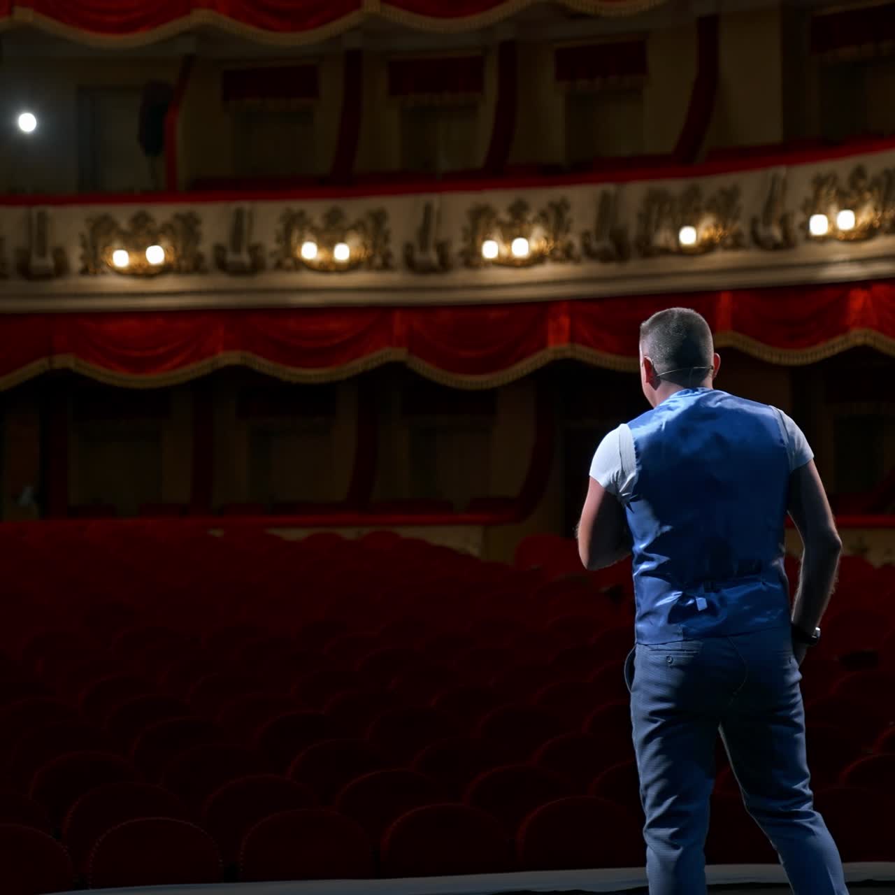 Rehearsal before the performance. Actor man is talking to the empty auditorium during pandemic in the world. Speaker talking in the theater with no people