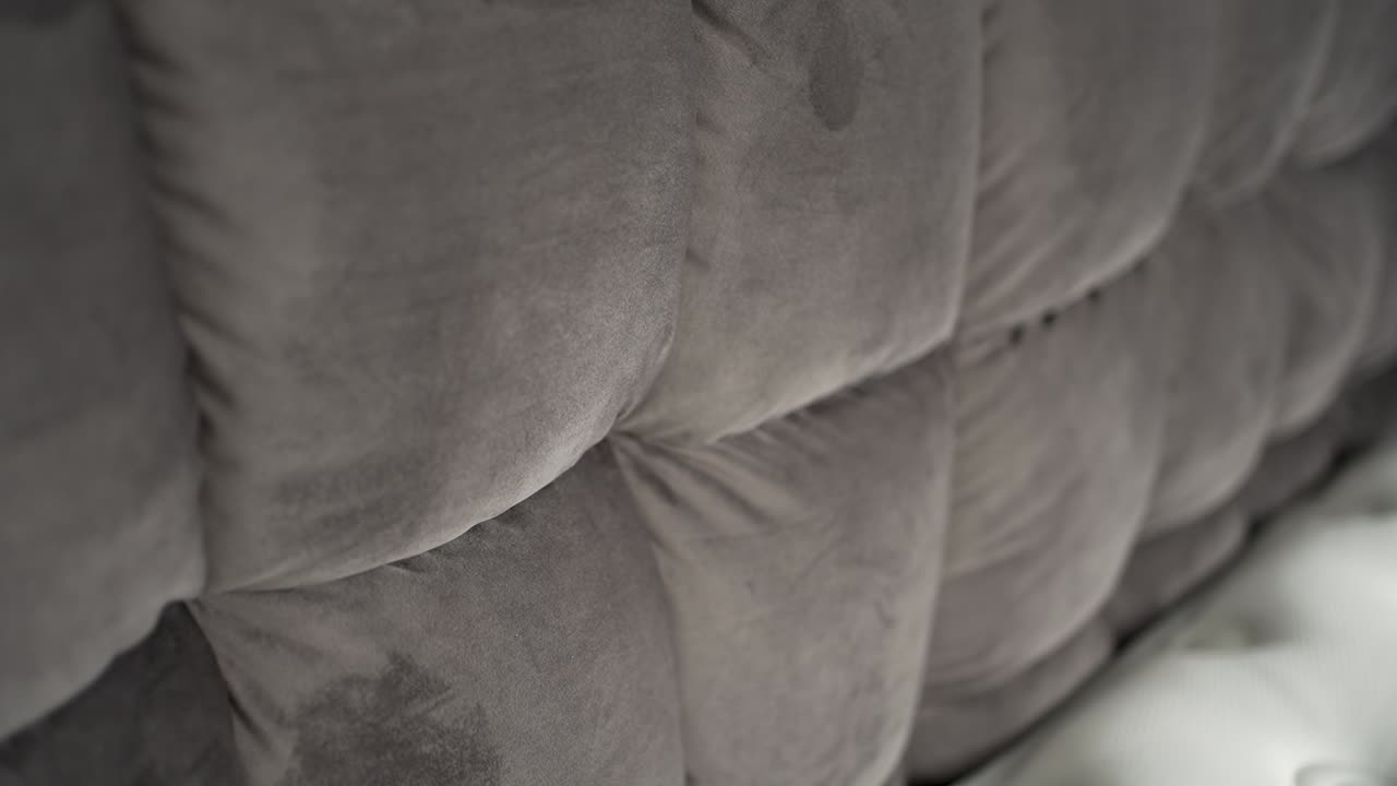 Soft, plush fabric is showcased, highlighting its texture and pattern in a comfortable interior setting. The close-up emphasizes the cozy and inviting feel of the material