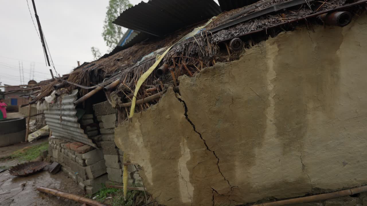 Immagini di una casa di fango in un villaggio che mostrano una struttura parzialmente crollata. Evidenzia l'architettura rurale, la costruzione tradizionale e la vita rustica del villaggio
