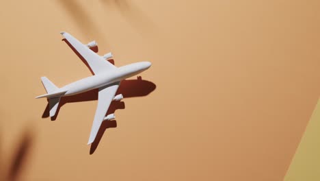 Nahaufnahme-Eines-Weißen-Flugzeugmodells-Mit-Blattschatten-Und-Kopierraum-Auf-Gelbem-Hintergrund