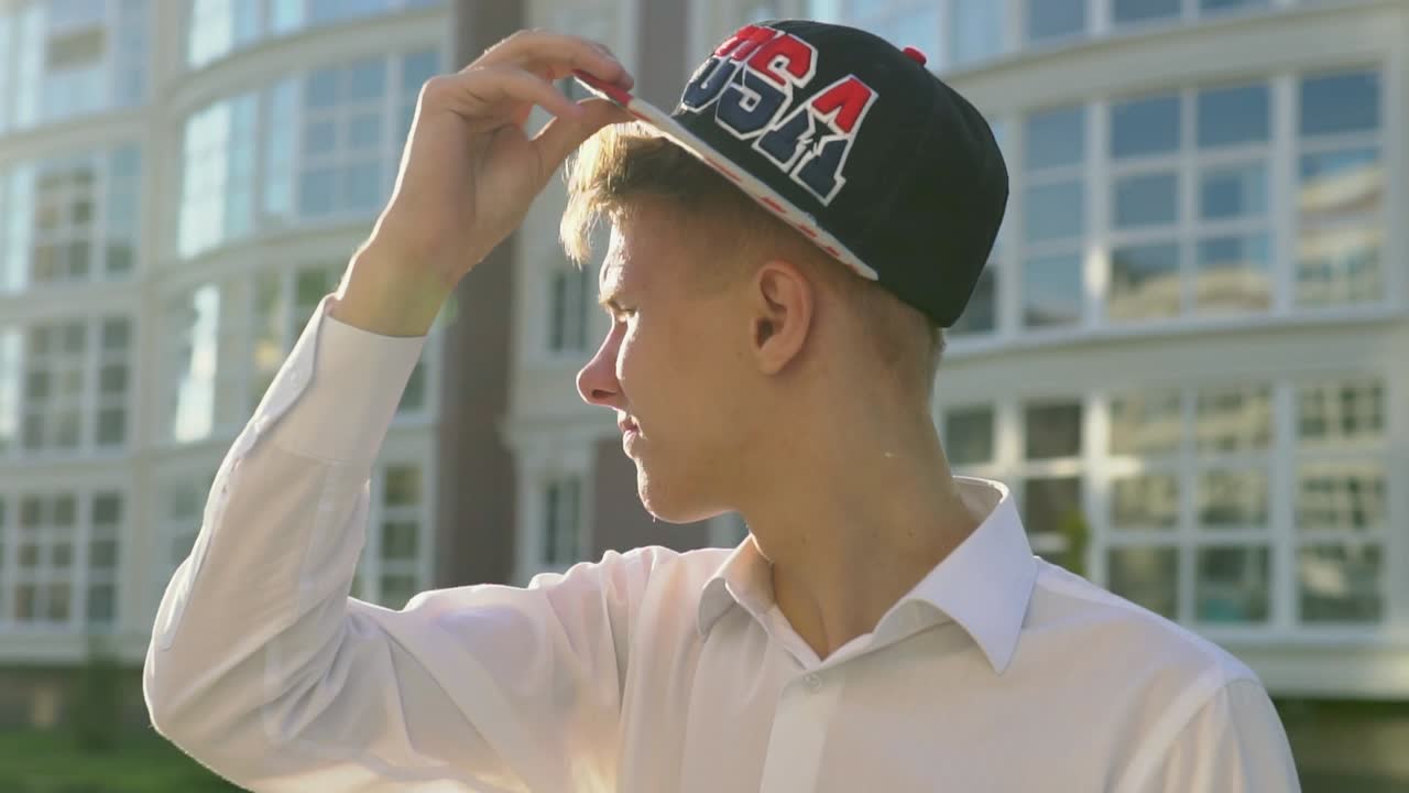Young Man Adjusting Hat in City