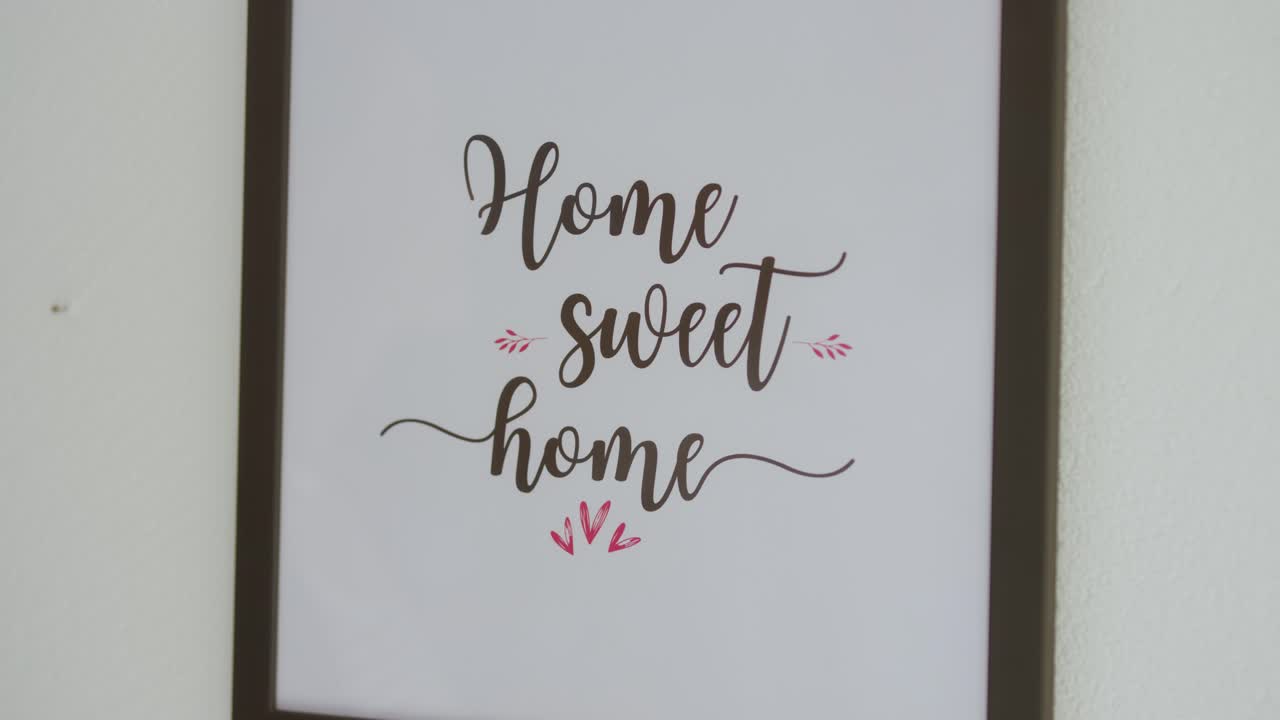 Woman hanging up "home sweet home" frame on wall