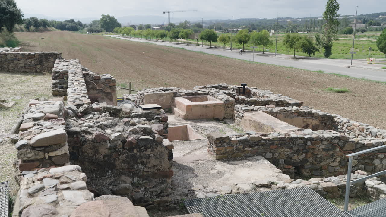 Un primer plano con movimiento de cámara revela la detallada obra en piedra y el diseño conservado del yacimiento arqueológico Villa romana de Can Terrers en España.