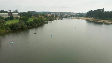 Aerial-panoramic-of-people-paddling-in-Cavado-River,-Esposende-Portugal