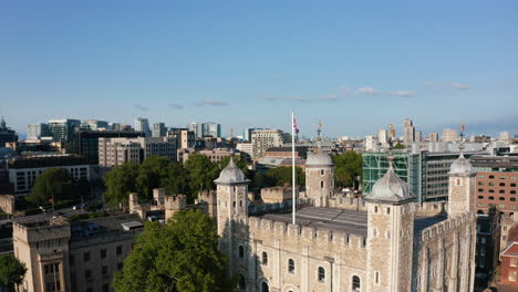 Panorama-curve-footage-of-top-of-White-Tower-and-surrounding-buildings.-Historic-medieval-part-of-Tower-of-London.-Union-jack-waving-in-wind.-London,-UK
