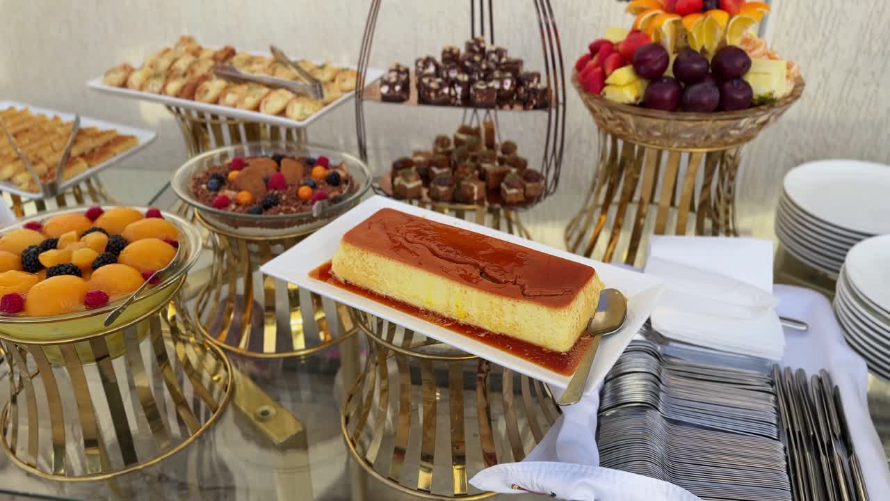 Una sontuosa tavola di dolci con un grande crème caramel, composizioni di frutta fresca e pasticcini gourmet assortiti in un evento di catering di lusso o in un buffet di un ristorante