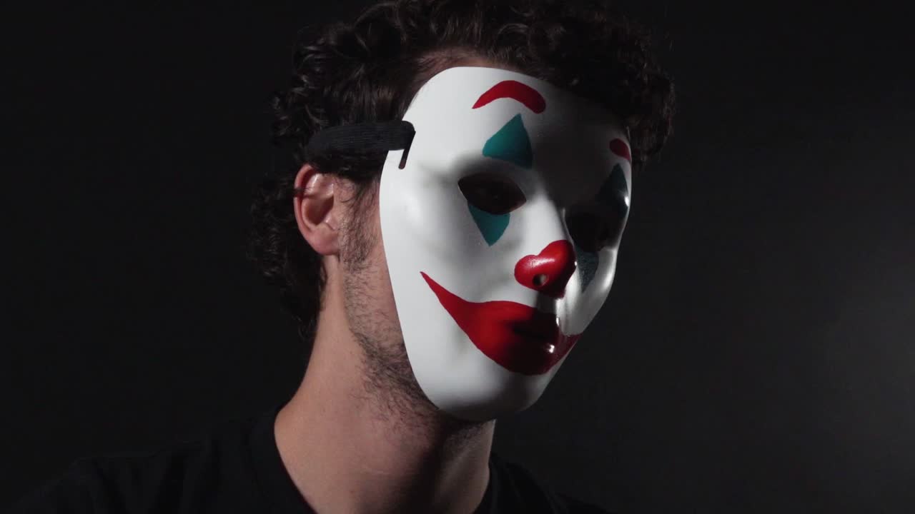 hombre que lleva la máscara de payaso con el tema del bromista en una habitación negra oscura