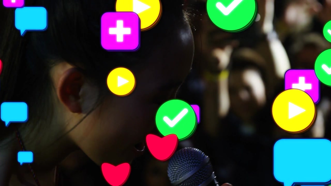 Camera cutting causing icons, singer singing into mic at dark venue, off-shoulder, phones for fans