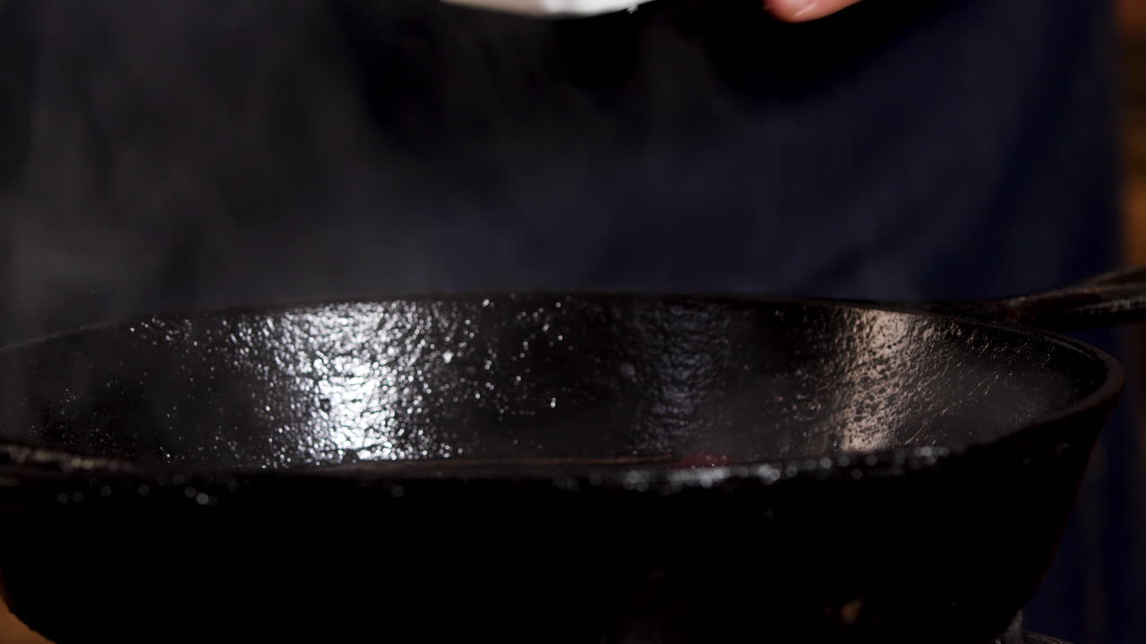Chef Seasoning Meat in Cast Iron Pan