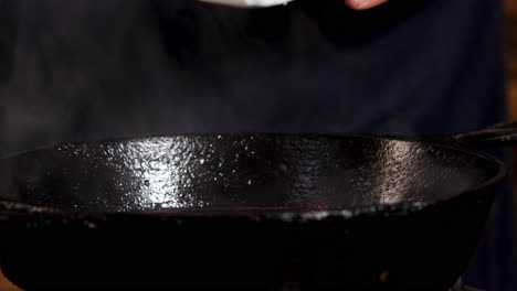 chef seasoning meat in cast iron pan
