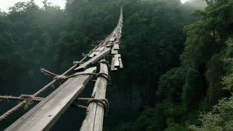 precarious wooden bridge over a deep forested gorge