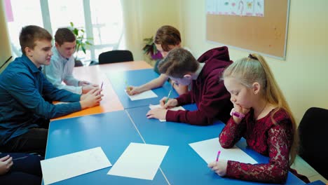 students in the classroom. pupils study at one big table together at private school. education concept.