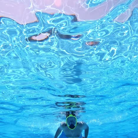 man diving in mask in the pool. blue transparent water and a strong male swimming under the water. underwater video.