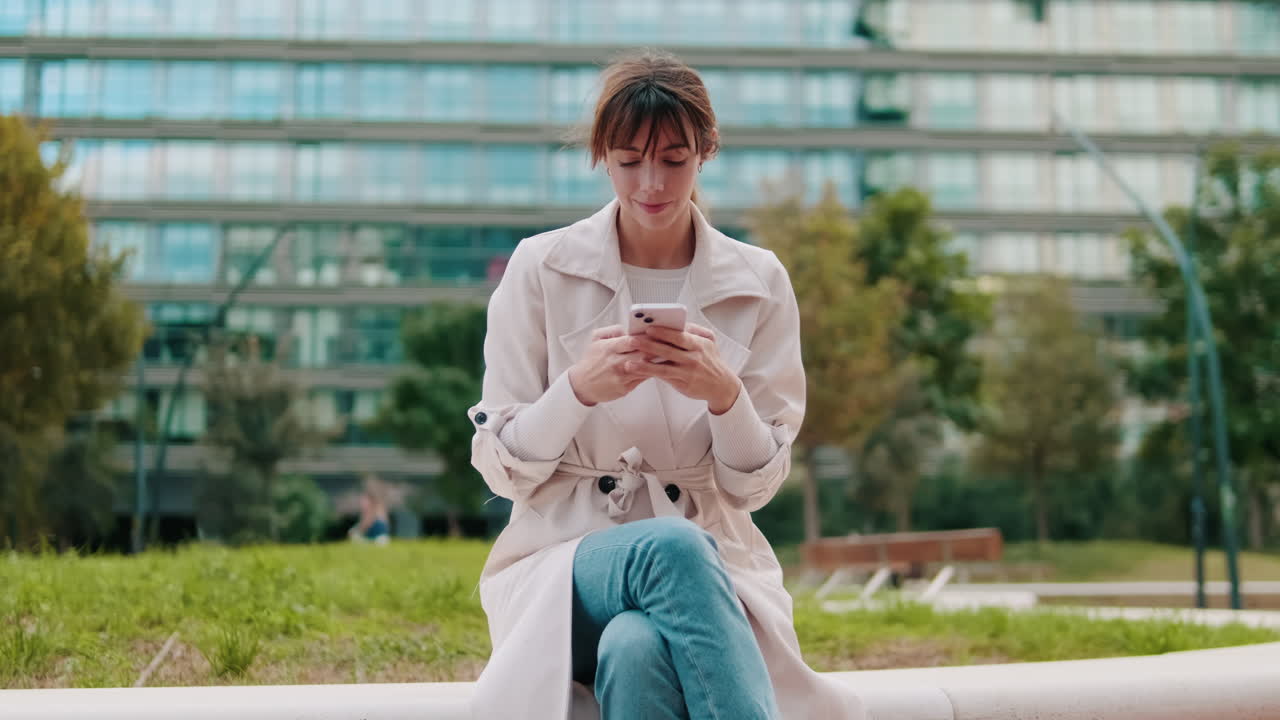 Giovane donna seduta all'aperto che usa il suo smartphone.
