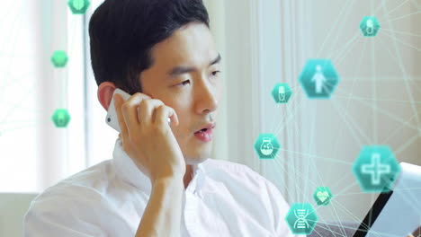 animation of connected icons globes, asian man looking at digital tablet and talking on smartphone