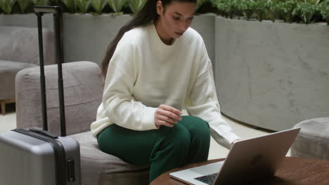 Mujer-Joven-Trabajando-Desde-El-Vestíbulo-Del-Hotel.