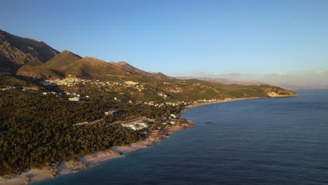 Holiday-paradise-on-sea-shore-of-Drimadhes-Albania-at-golden-hour,-resorts-near-beach-surrounded-by-green-trees