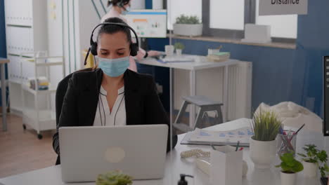 freelancer con mascarilla protectora usando auriculares mientras habla en el micrófono