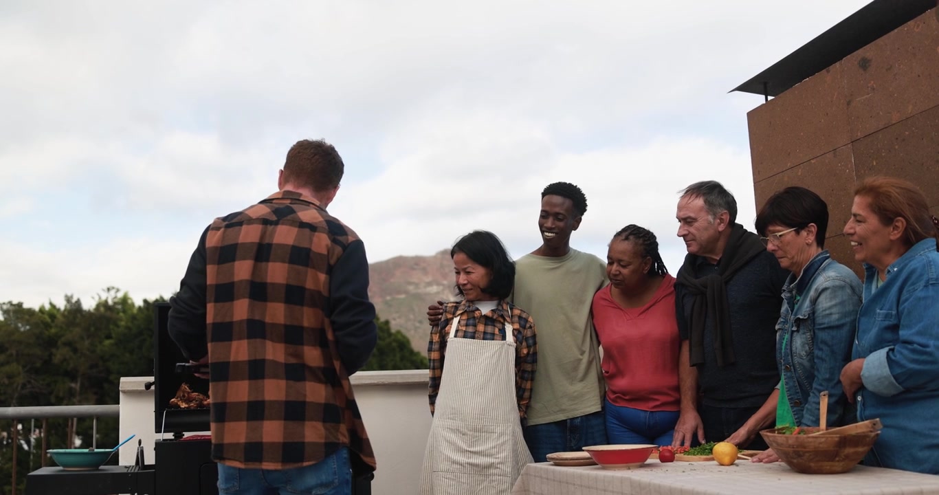 Amigos multiétnicos disfrutando de una parrillada en una terraza en la azotea