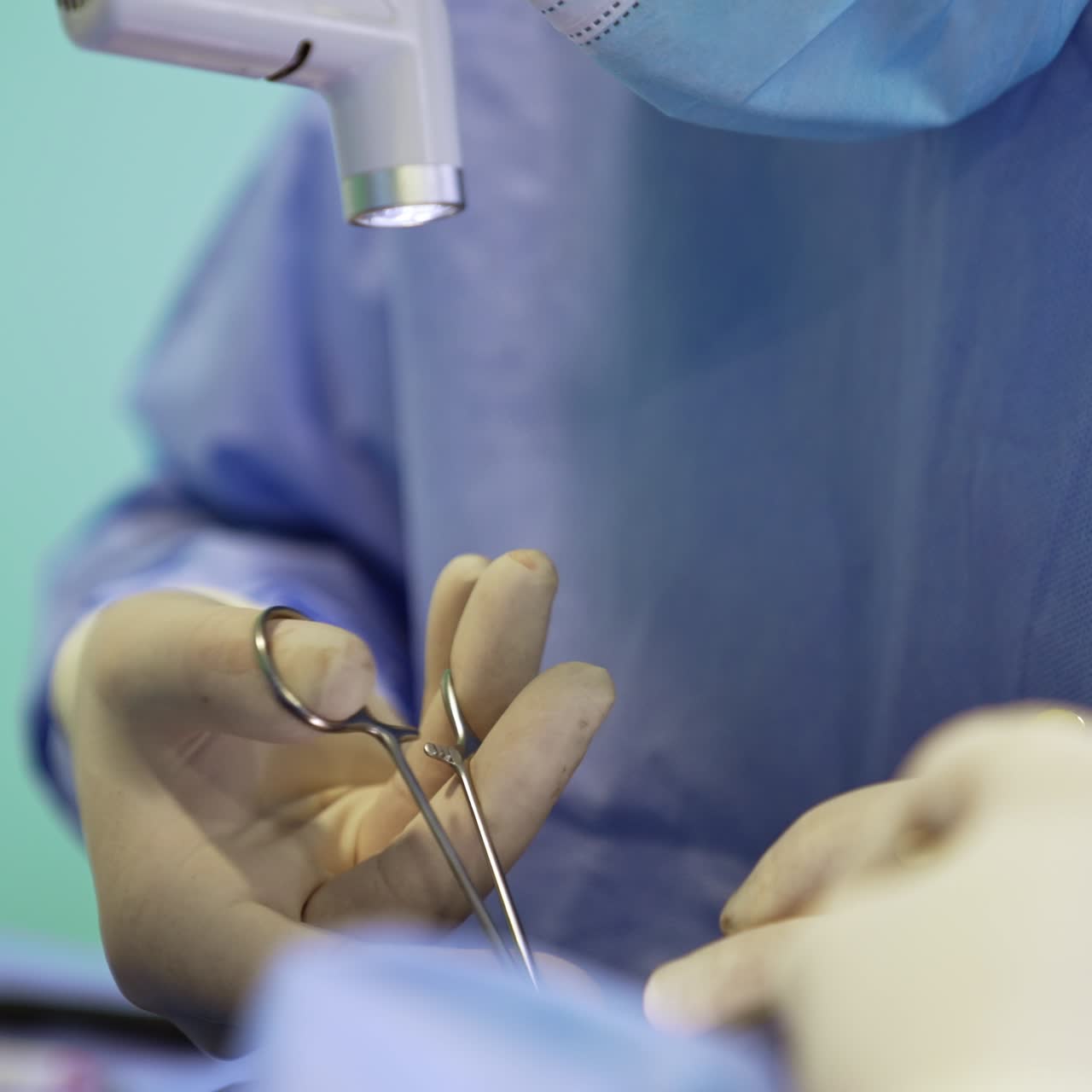 Hands of surgeon in gloves using the forceps. Surgical procedure close up