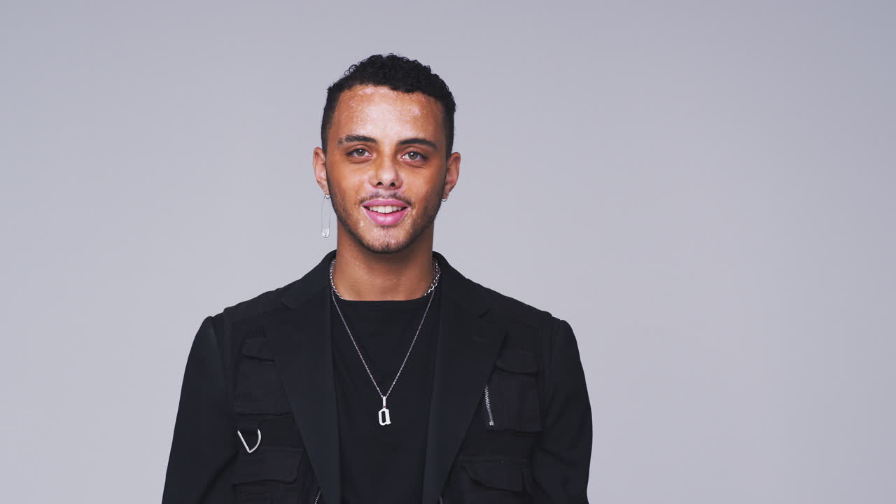 scatto in studio di un giovane con disturbo della pigmentazione della pelle che sorride alla telecamera in slow motion