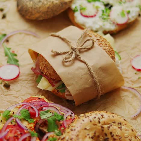 bagels with ham  cream cheese  hummus  radish wrapped in brown baking paper ready for take away