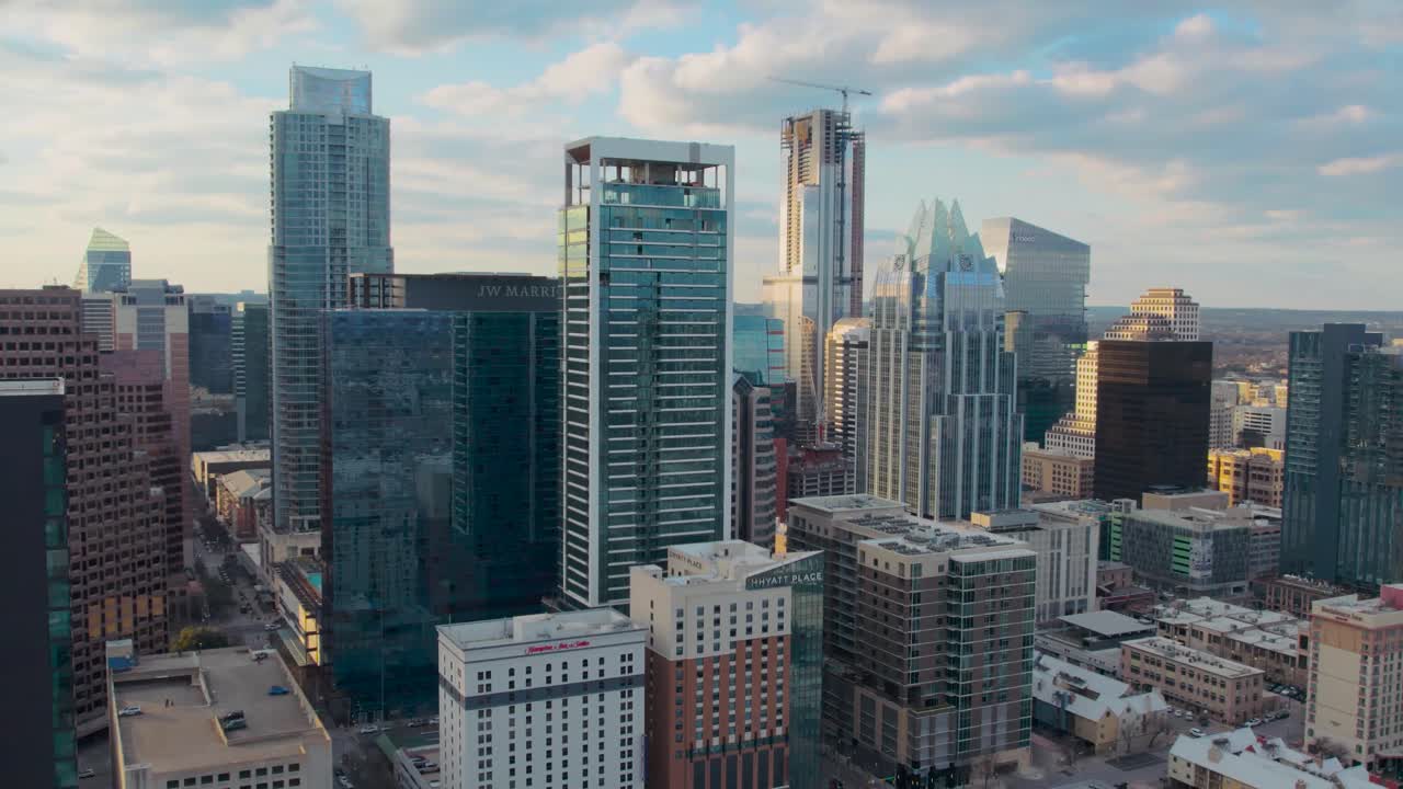 vuelo de drones austin texas icónico centro de la ciudad distrito de la torre con vistas a la torre de frost bank, el austonian, jw marriott hotel, y el westin en una hermosa puesta de sol dorada con nubes