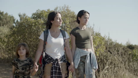 two sisters and little brother walking along dirt road and talking together