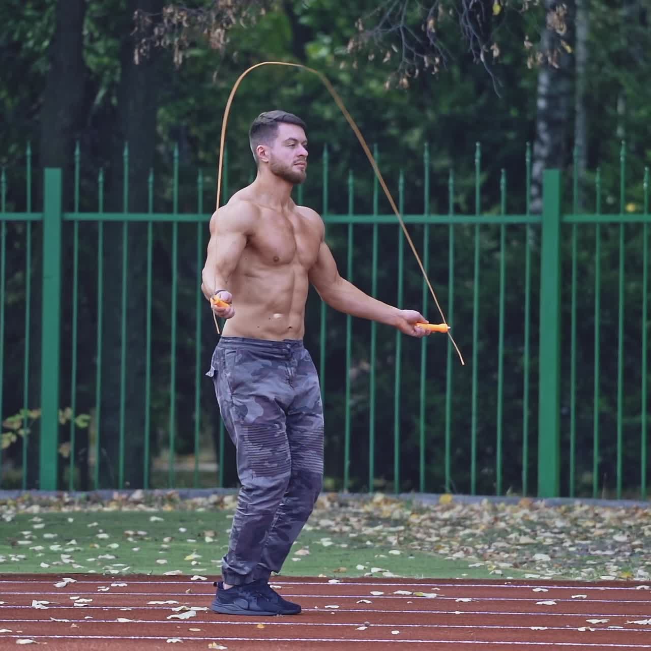 . Man exercising with jumping rope. Yong handsome fit man jumping rope on stadium