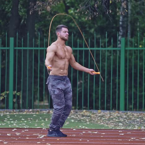 . man exercising with jumping rope. yong handsome fit man jumping rope on stadium