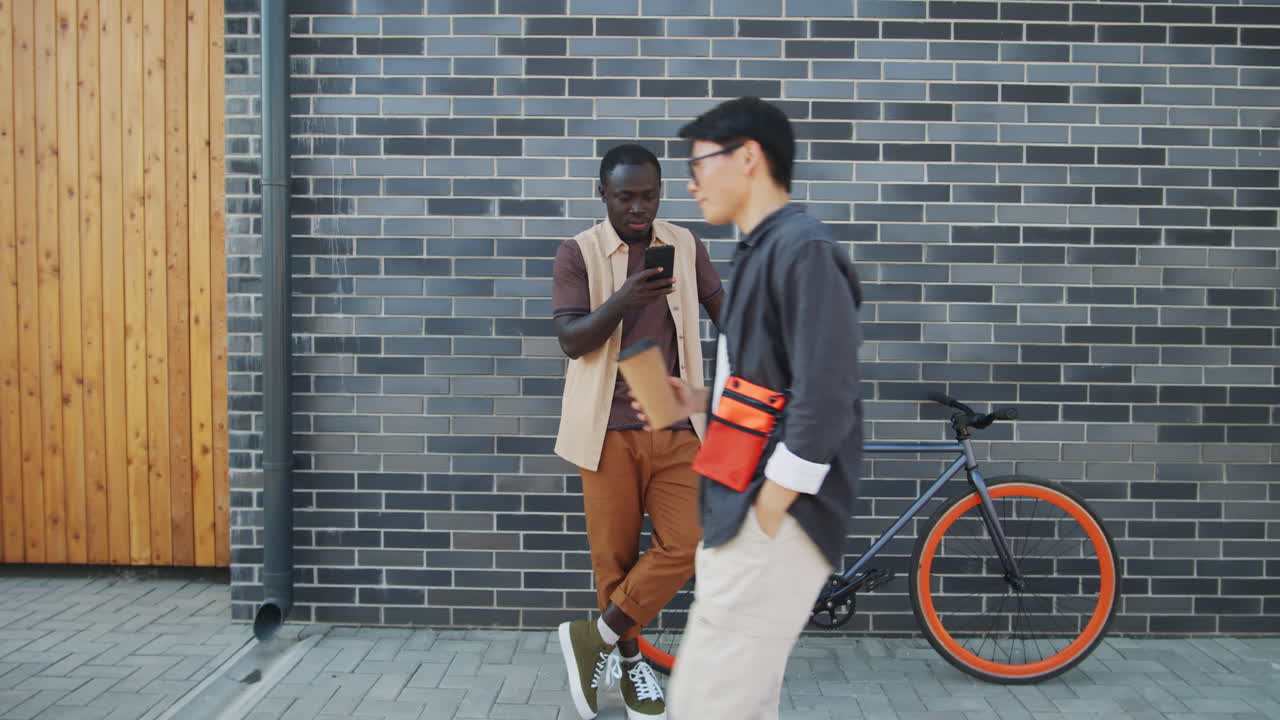 African American Man Standing with Bike on Street and Using Smartphone