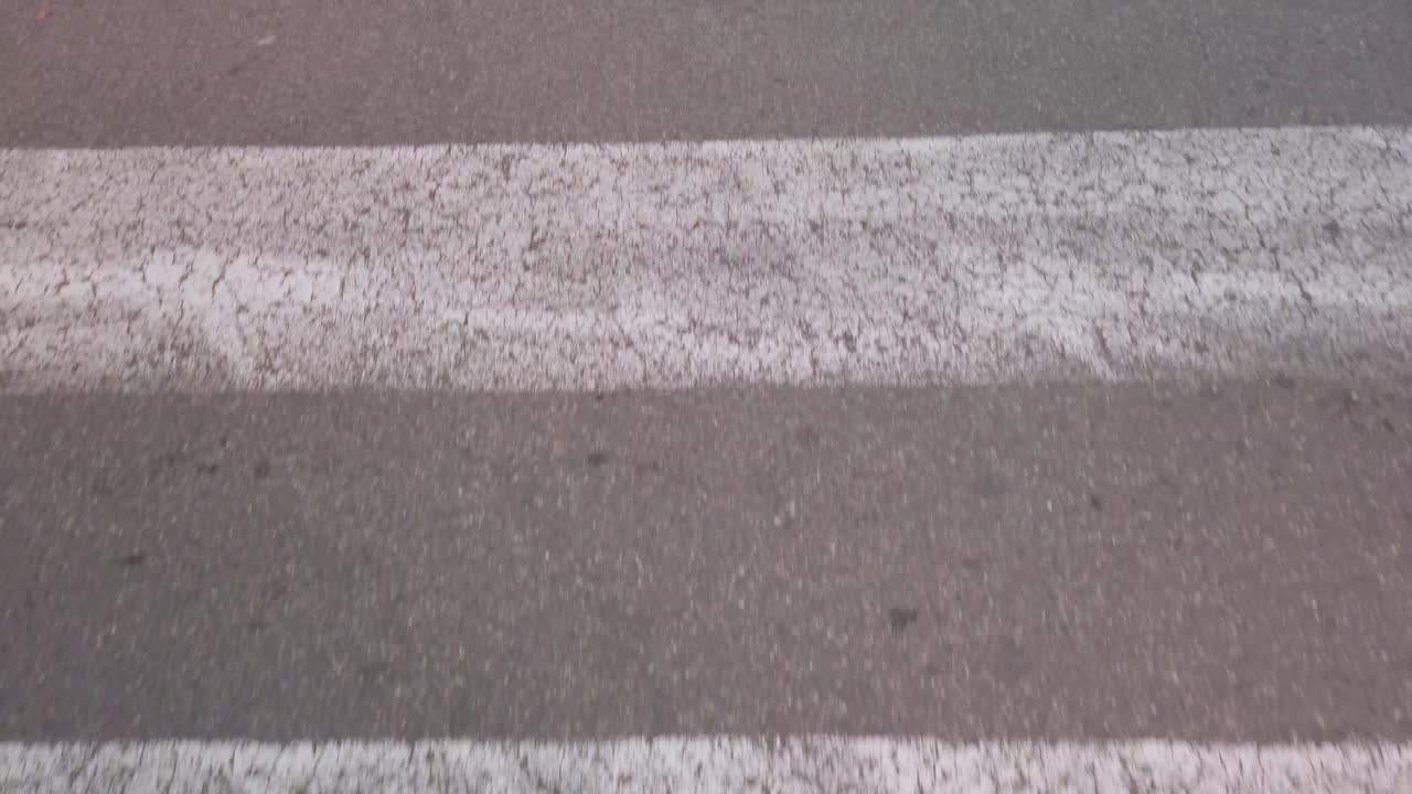 Cracked paint lines of crosswalk pedestrian crossing, Close Up Moving Forward