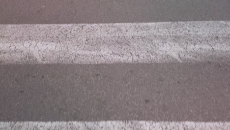 cracked paint lines of crosswalk pedestrian crossing, close up moving forward