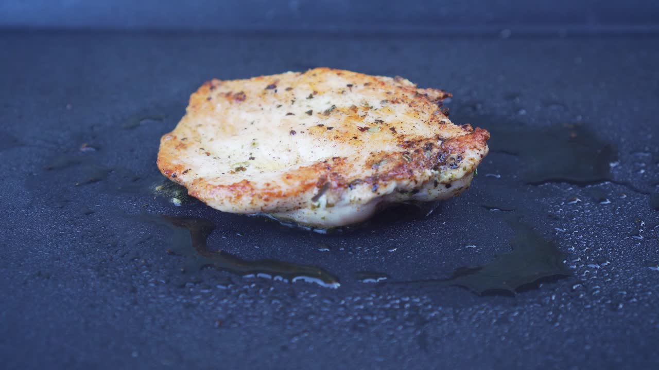 Turning chicken meat on grill pan, extreme closeup
