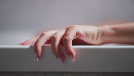 woman hand on bathtub edge at home closeup. lady enjoys recreational procedures bathing in luxury spa salon. woman takes warm bath to relax body