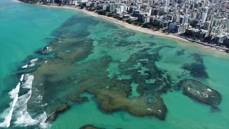 Hermosos-Arrecifes-De-Colores-Desde-Arriba-Y-La-Ciudad-De-Maceio,-Rascacielos-De-Viaje