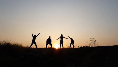 silhouetted group of people jumping up during sunset in slow motion