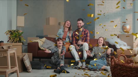 young happy family with two children sit down on couch celebrating buying, moving in new apartment with confetti cannon.