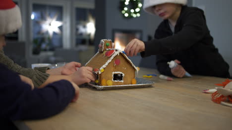 kids decorating a gingerbread house together with christmas candy, cozy holiday vibe indoors