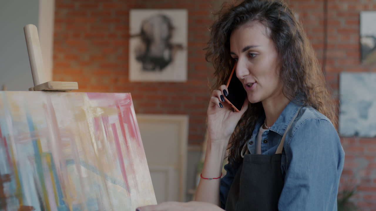 Artista che parla al telefono della sua opera d'arte in studio