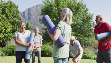 Eine-Vielfältige-Gruppe-Glücklicher-Senioren-Und-Seniorinnen-Unterhält-Sich-Nach-Dem-Training-Im-Garten,-Zeitlupe